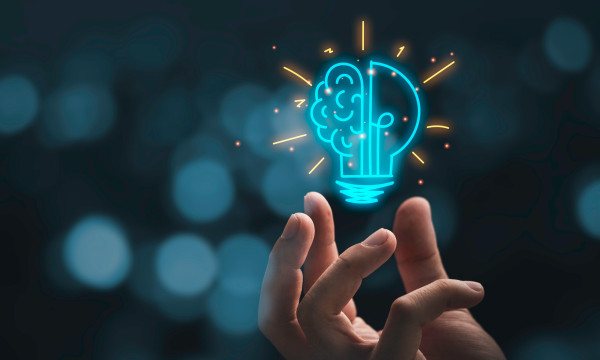a hand hovering below a blue light bulb