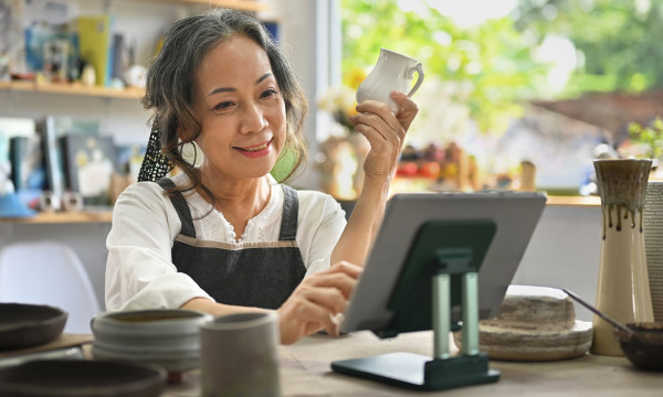 a woman with her phone in her hand looks at a tablet smiling