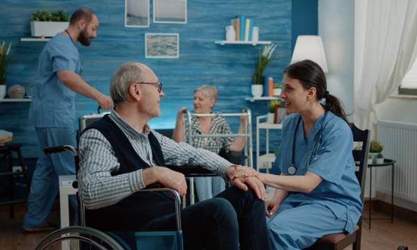 an elderly patient sits with a male and female nurse in a home