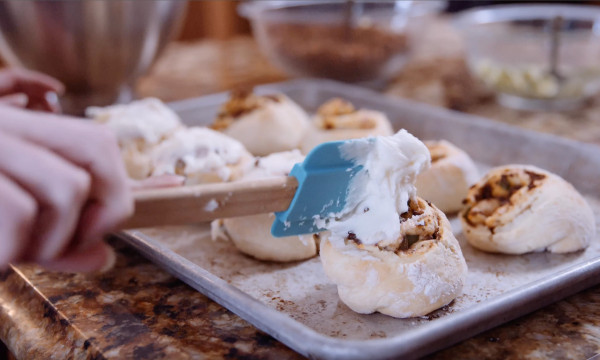 icing gets spread on a cinnamon roll