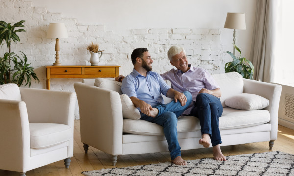 a young man sits with an older man on a couch