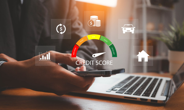 a person sits at their laptop with a credit score graphic laid over image