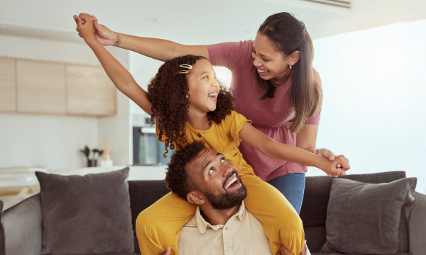 a mom, dad, and daughter play together laughing