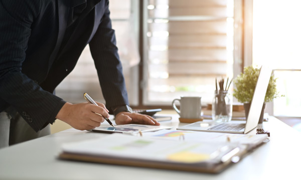 a person stands at a desk writing