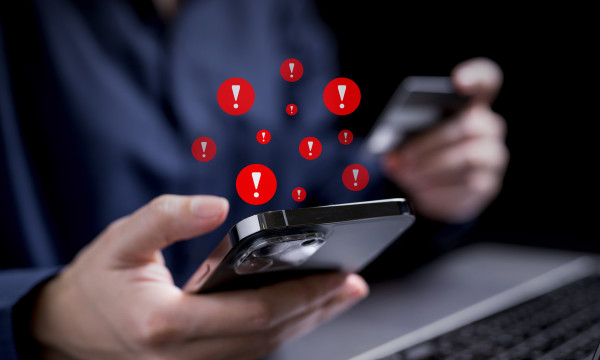 a person holds a phone with red exclamation marks coming out of it