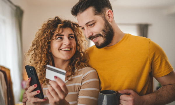 a happy couple stands together holding a debit card