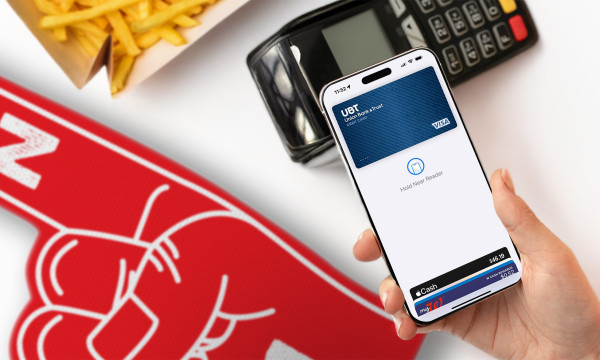 a hand holds a phone near a payment reader, fries, and a red foam finger