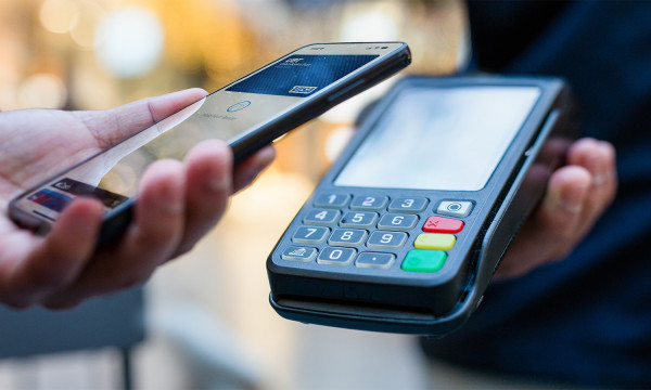 a person holds a phone near a payment machine