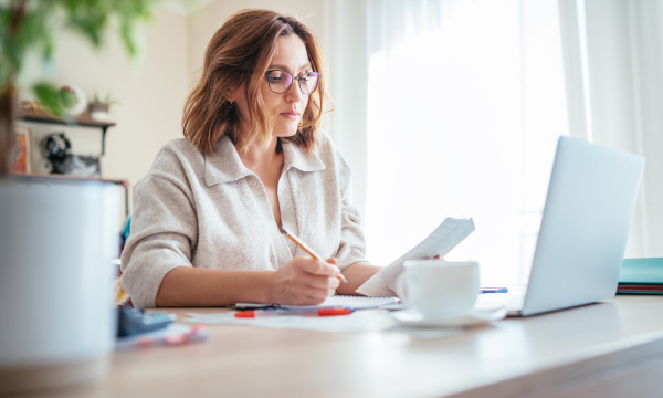 a woman sits at her laptop at a table