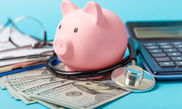 A piggy bank standing on cash next to a calculator