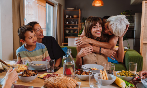 a family sits around a table laughing and hugging
