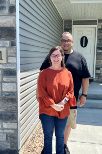 A couple standing outside of their new home. 