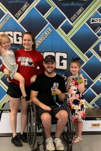 A man in wheelchair posing with is wife and two young kids at the CSG wheelchair awards